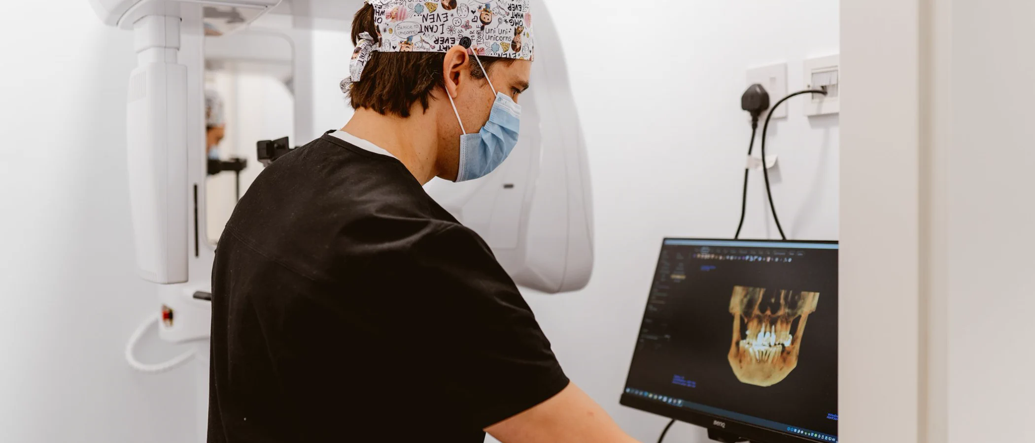 A Maida Smiles clinician reviews a 3D jaw scan beside the CBCT scanner.