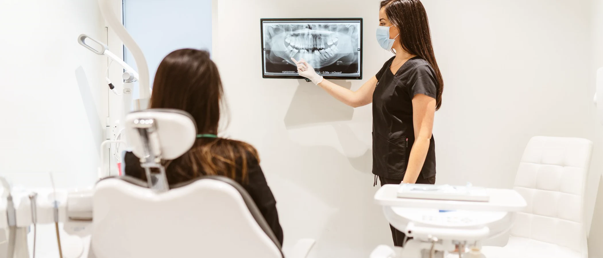 A dentist explains a panoramic dental X-ray to a seated patient at Maida Smiles.