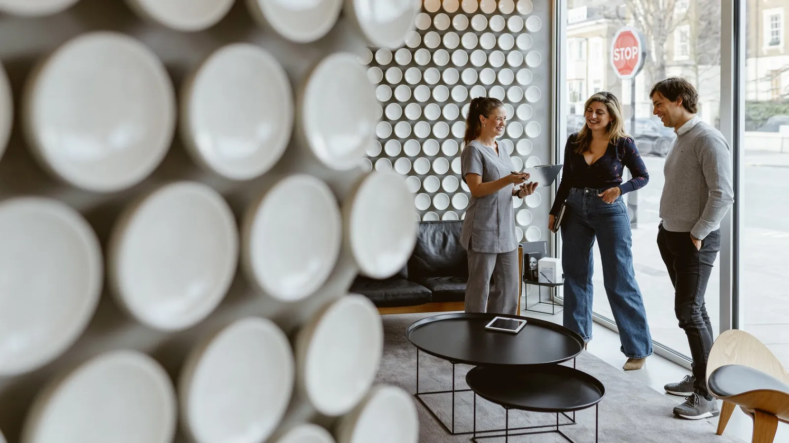Dental clinician speaking with two visitors in a bright London clinic lounge