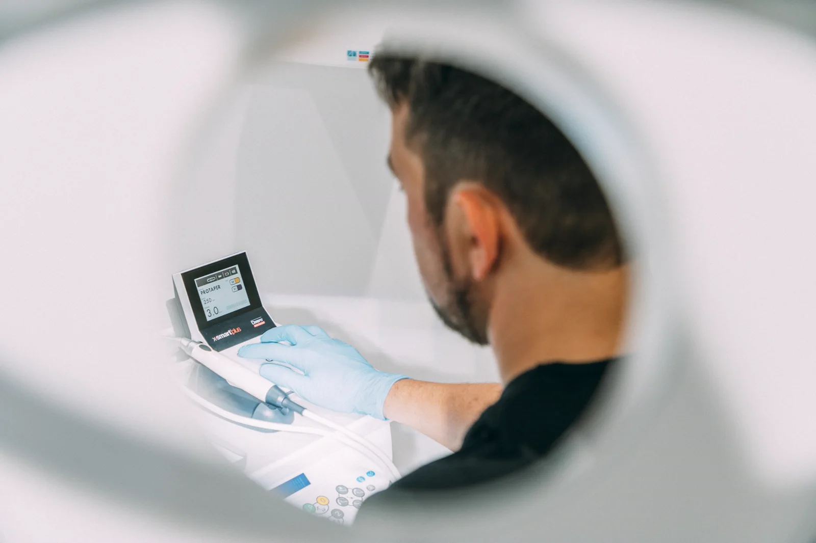 A clinician operates a modern endodontic motor in the treatment room.