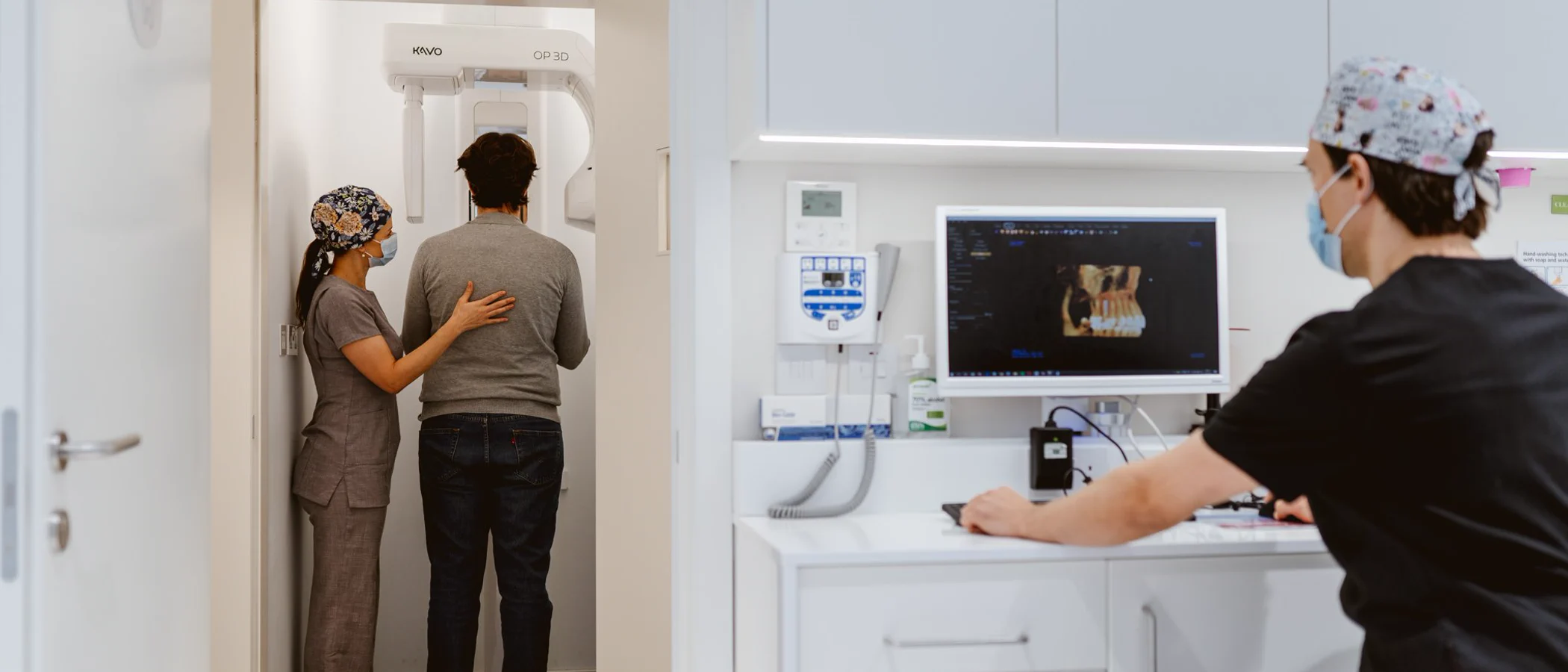 A dental assistant supports a patient during a CBCT scan while a colleague reviews the image.